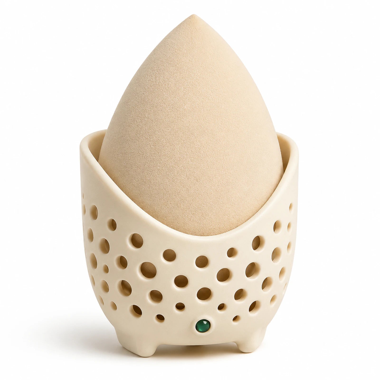 MUSEVA teardrop makeup sponge in a perforated holder on a warm ivory background.