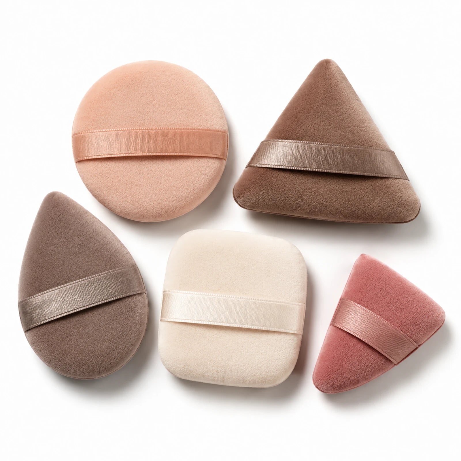 Five neutral-tone MUSEVA makeup puffs in different shapes on a warm ivory background.